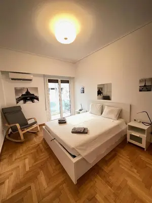 a bedroom with a large white bed and a chair at Olympic Hadrian Apartment next to Acropolis in Athens
