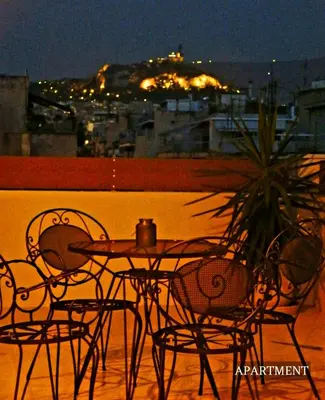 a table and chairs on a balcony at night at Sunkissed Terrace Apartments in Athens