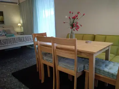 a dining room table and chairs with a vase of flowers at blue cielo sunny apartment in Palaiá Fókaia