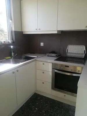 a kitchen with white cabinets and a sink and a stove at blue cielo sunny apartment in Palaiá Fókaia