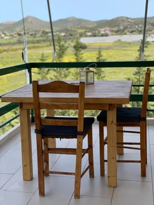 a wooden table and two chairs with a view at blue cielo sunny apartment in Palaiá Fókaia