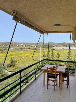 a table and chairs on a balcony with a view of a field at blue cielo sunny apartment in Palaiá Fókaia