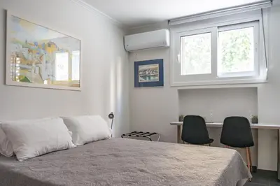 a bedroom with a bed with two chairs and two windows at Pan's Cave Studio in Plaka in Athens