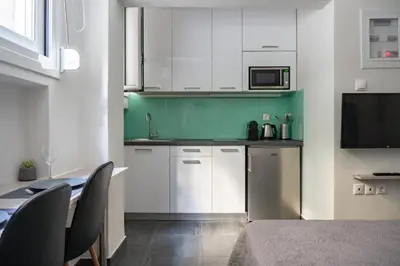 a kitchen with white cabinets and a table with chairs at Pan's Cave Studio in Plaka in Athens