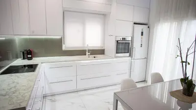 a white kitchen with white cabinets and a refrigerator at Luxury Apt 115m2 in Athens