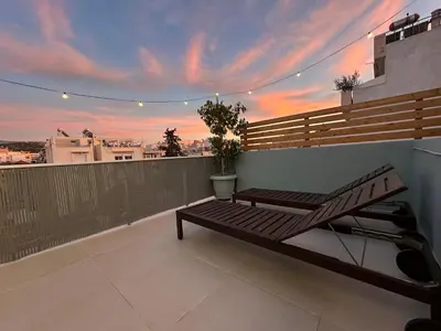 a bench on a balcony with a sunset in the background at Luxury Apt 115m2 in Athens