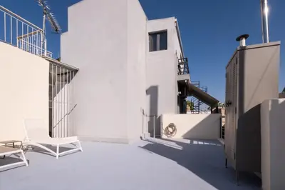 a patio with white chairs on the side of a building at THISIO LOFT in Athens