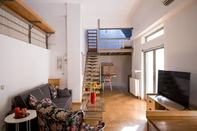 a living room with a couch and a staircase at THISIO LOFT in Athens