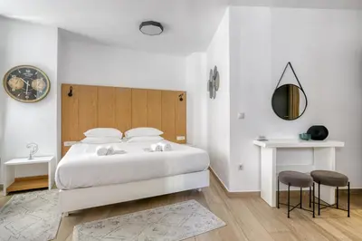 a white bedroom with a white bed and a mirror at Elia Kolonaki Luxury Apartments in Athens