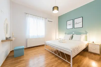 a bedroom with a white bed with a blue headboard at Athens Central Pangrati - Varnava Square Modern Apartment for 5 in Athens