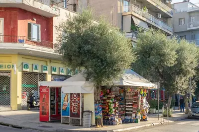 a shop on a city street with trees and buildings at IVY Muse 1BR Apartment in Neos Kosmos Athens in Athens