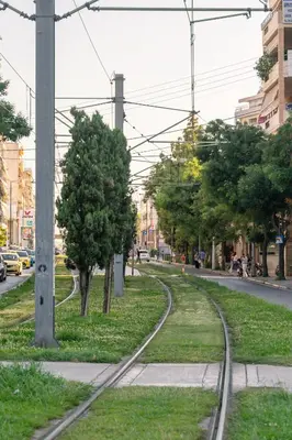a set of train tracks on a street with trees at IVY Muse 1BR Apartment in Neos Kosmos Athens in Athens