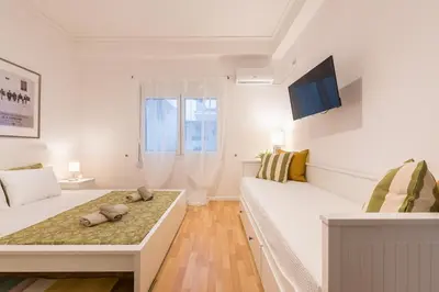 a white room with two beds and a tv at Apartment at Megaro Mousikis st semi basement 1bed 2 pers by MPS in Athens