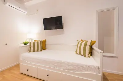 a white bedroom with a bed with a tv on the wall at Apartment at Megaro Mousikis st semi basement 1bed 2 pers by MPS in Athens
