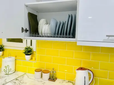 a kitchen with yellow tiles and a shelf with dishes at Lemoni Garden Apartment VIPGreece in Athens