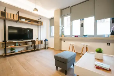 a living room with a large tv and a table at Athenian Living Suites in Athens
