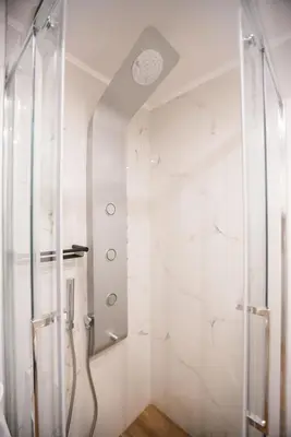 a shower in a bathroom with white marble walls at Athenian Living Suites in Athens