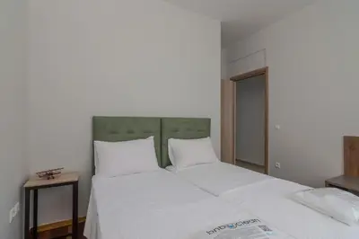 a large bed with white sheets and a green headboard at 105 Adrianou Plaka in Athens