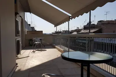 a balcony with a table and chairs on a roof at Double Apartment - Athens Center, 7 BD, 3 BATH in Athens