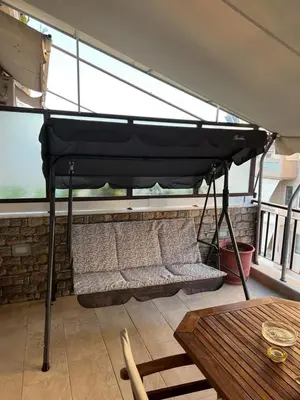 a swing bed on a balcony with a table at Athens Nautical Flat in Piraeus