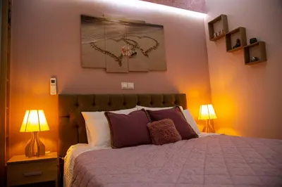 a bedroom with a bed with two lamps and a painting at Athens Nautical Flat in Piraeus