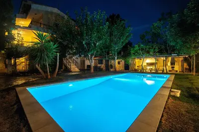 a swimming pool lit up at night at VILLA ELENI in Anavissos