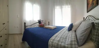 a bedroom with a bed with a blue comforter at House Sleeps 4 with Pets in Kalívia Thorikoú