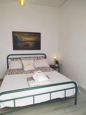 a bedroom with a large bed with white sheets at House Sleeps 4 with Pets in Kalívia Thorikoú