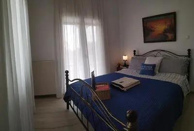 a bedroom with a bed with a blue comforter at House Sleeps 4 with Pets in Kalívia Thorikoú