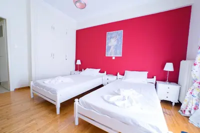 two beds in a room with a red wall at Athens Colors Suite in Athens
