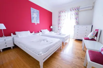 two beds in a room with a red wall at Athens Colors Suite in Athens