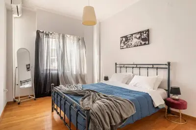 a bedroom with a bed with a blue blanket and a window at Eχquisite apt in Acropolis-plaka/vaccinatedHost in Athens
