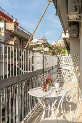 a white table on a balcony with a table and flowers at Eχquisite apt in Acropolis-plaka/vaccinatedHost in Athens