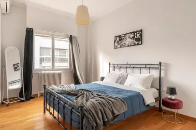 a bedroom with a bed with blue sheets and a window at Eχquisite apt in Acropolis-plaka/vaccinatedHost in Athens