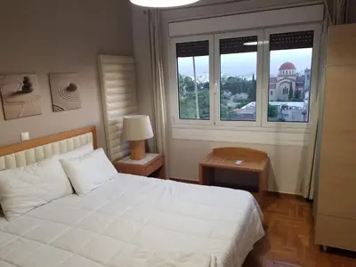 a bedroom with a white bed and two windows at ENILION ATHENS , CITY CENTER WITH VIEW TO ACROPOLIS in Athens