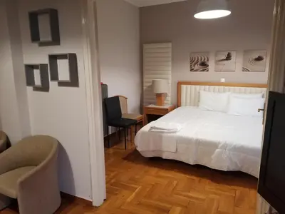 a bedroom with a white bed and a chair at ENILION ATHENS , CITY CENTER WITH VIEW TO ACROPOLIS in Athens