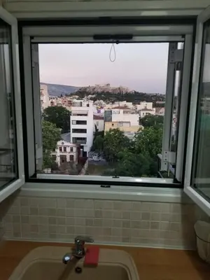 a window over a sink with a view of a city at ENILION ATHENS , CITY CENTER WITH VIEW TO ACROPOLIS in Athens