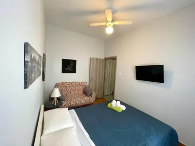 a bedroom with a bed and a couch and a ceiling fan at Luxury Flat in Hilton, 3' from metro, VFM! in Athens