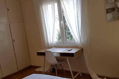 a desk in front of a window with a white curtain at Blue Apartment - Athens Center, 4 BD, 2 BATH in Athens