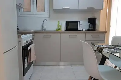 a kitchen with white cabinets and a table and a microwave at Blue Apartment - Athens Center, 4 BD, 2 BATH in Athens