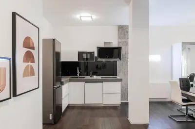 a kitchen with white cabinets and a black refrigerator at Industrial 1BR Apartment in Ampelokipoi Area by UPSTREET in Athens