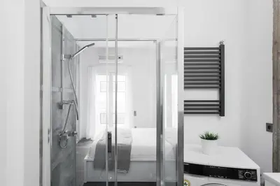 a glass shower in a bathroom with a bed at Industrial 1BR Apartment in Ampelokipoi Area by UPSTREET in Athens