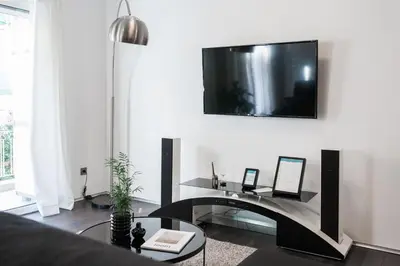 a living room with a table and a tv on the wall at Industrial 1BR Apartment in Ampelokipoi Area by UPSTREET in Athens