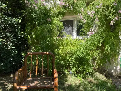 a bench sitting in the grass in front of a house at the garden house in Dhaskalión