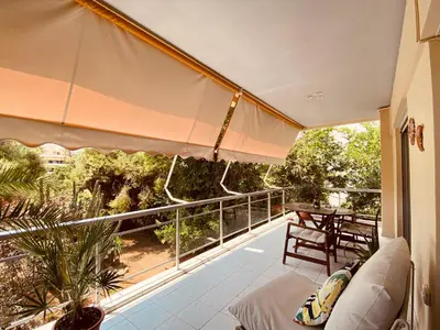 a balcony with a couch and an umbrella at Athens Riviera Garden Views Apartment #Unoblu in Athens