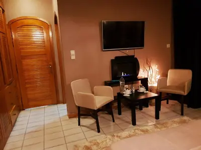 a living room with a table and chairs and a television at Kouro's private room! in Piraeus