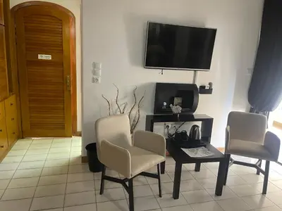 a living room with two chairs and a table and a tv at Kouro's private room! in Piraeus