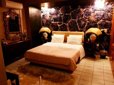 a bedroom with a bed and a stone wall at Kouro's private room! in Piraeus