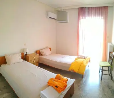 a bedroom with two beds and a window and a chair at Vangelis apartment near Athens Airport in Spáta
