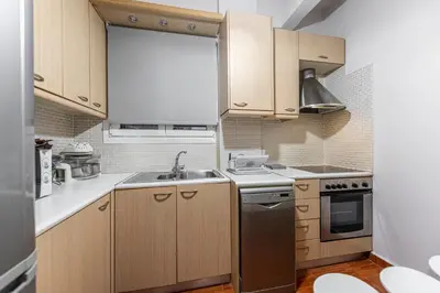 a small kitchen with wooden cabinets and a sink at Alopece City Apartment - Kolonaki in Athens